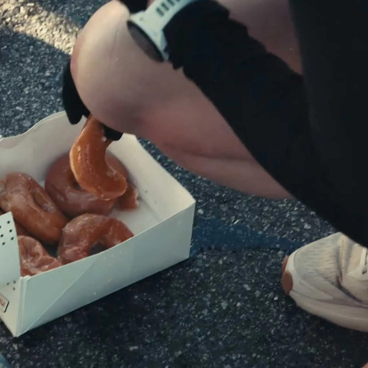 Elizabeth reaching into a box of Krispy Kreme doughnuts